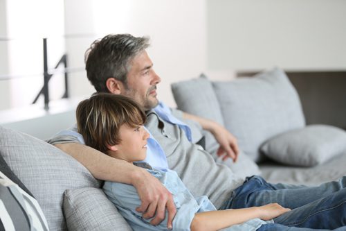 A Parent’s Guide to Age-Appropriate Conversations on Substance Use - man sitting on couch with adolescent son
