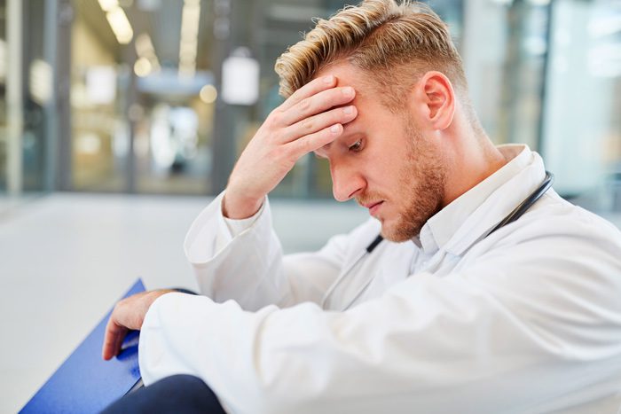 male doctor looking stressed sitting on ground - professionals