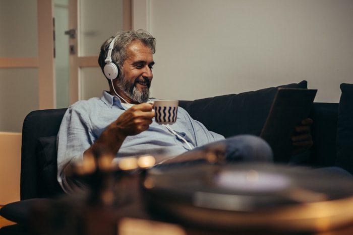 older man at home drinking coffee and listening to music